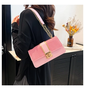 Detail of pink patchwork crossbody bag with gold lock and chain strap on a model