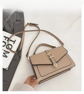 Detailed view of beige crossbody bag with golden hardware buckle and top handle strap