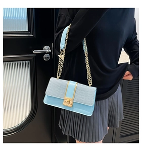 Detail of light blue patchwork bag with woven texture and gold chain strap on model