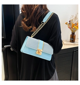 Close-up of light blue tweed crossbody bag with gold chain and elegant metal buckle