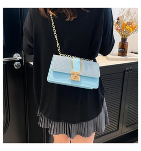 Woman wearing light blue contrast square bag with gold chain strap and metal lock