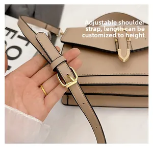 Detail of adjustable shoulder strap with gold buckle on a beige square crossbody bag