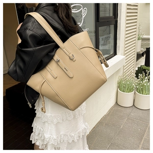 Detail of large beige tote bag with textured pebbled leather and metal buckle closure