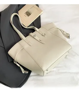 Detail of cream lychee leather tote bag with drawstring sides and metal hardware accents