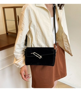 Detail of a black matte crossbody square bag featuring a modern silver metal buckle clasp