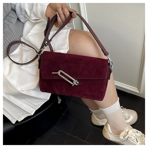 Detail shot of burgundy suede shoulder bag featuring a unique silver pin lock buckle