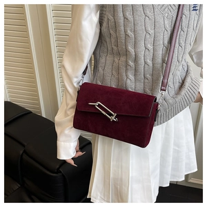 Deep red suede crossbody bag featuring a minimalist silver bar lock and slim shoulder strap