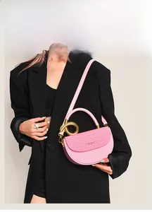 Detail der rosa Satteltasche mit goldenem Metallringgriff und strukturierter Kunstleder-Oberfläche