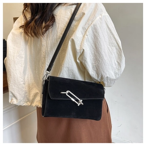 Close-up of black matte leather crossbody bag featuring a chunky silver chain buckle