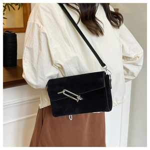 Detailed view of black suede crossbody bag featuring a unique silver oval metal buckle