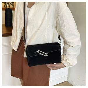 Detail of black suede crossbody bag with decorative silver metal interlocking rings