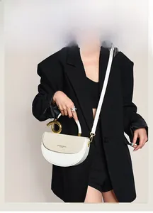 Detail der weißen Halbmond-Tasche mit gewebter Textur und großem goldenem Metallgriff