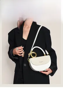 Detail der weißen Satteltasche mit goldenem Griff auf einem schwarzen Anzugmodell