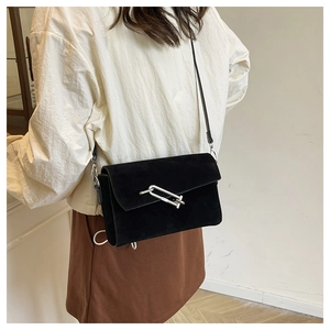 Side view of a black suede crossbody square bag with a silver U-shaped metal lock