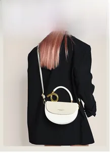 Schicke cremefarbene Satteltasche mit Goldgriff und langem Schultergurt am Modell