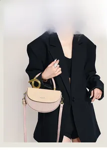 Rosa-beige Satteltasche mit gewebter Klappe und goldenem Ringgriff am Modell