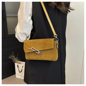 Detail of vintage yellow crossbody bag featuring a unique silver safety pin metal buckle