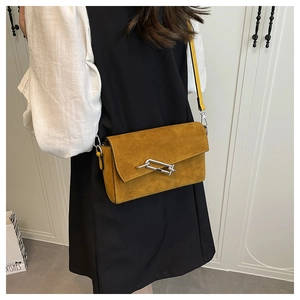 Close-up of mustard yellow square bag with silver interlocking metal clasp detail