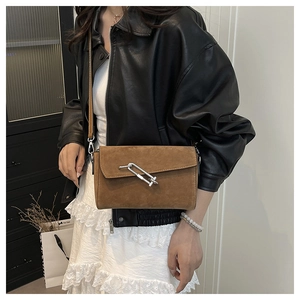 Close-up of brown suede crossbody bag with vintage silver metal lock buckle worn by model