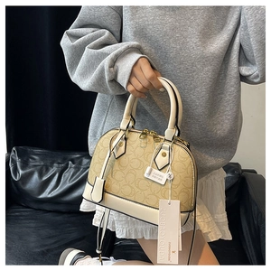 Dettaglio ravvicinato di una borsa a conchiglia vintage con stampa monogramma e oro