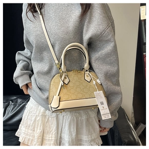 Dettaglio borsa a conchiglia vintage beige con motivo classico e finiture dorate