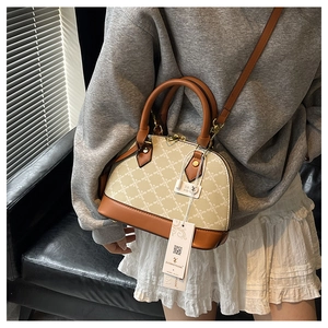 Dettaglio ravvicinato della borsa beige con motivo geometrico e finiture in pelle marrone