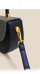 Detail der goldenen Metallteile und Webstruktur an einer schwarzen Sattelschultertasche