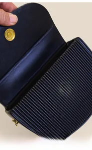 Detail der schwarzen Plissee-Handtasche mit goldenem Magnetverschluss und Innenfutter