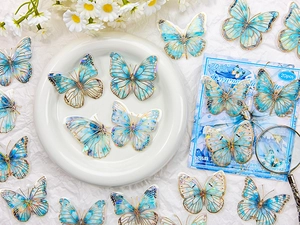 Close-up of blue PET butterfly stickers with gold foil details and 3D visual effect