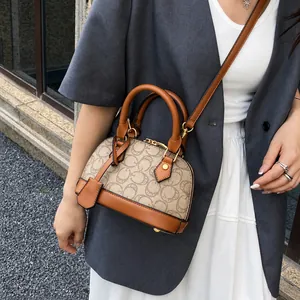 Dettaglio della borsa a conchiglia vintage con manici in pelle e tracolla su una modella
