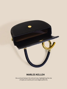 Detailansicht der schwarzen Ledertasche mit Faltenstruktur und goldenem Magnetverschluss