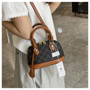 Dettaglio borsa vintage con motivo monogramma grigio, manici in pelle e cerniere dorate