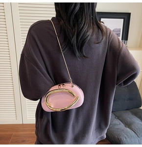 Detail of light pink patent leather shell bag with gold handle and metal chain strap