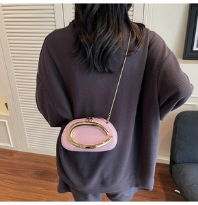 Back view of model wearing pink leather pillow bag with gold metal C-shaped accent