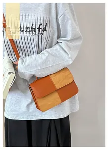 Detail of color-block crossbody bag featuring orange leather and beige textured panels
