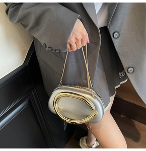 Close-up of metallic silver clutch with gold C-logo buckle and delicate snake chain