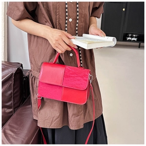 Detail of red patchwork leather handbag with smooth and pleated textures on a sofa