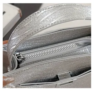Detailed close-up of the smooth silver zipper and metallic texture on a chic handbag