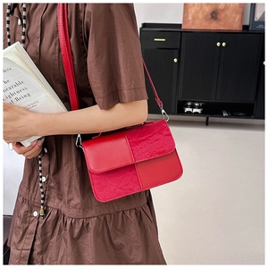 Close-up of red patchwork handbag showing textured leather details and silver metal hardware