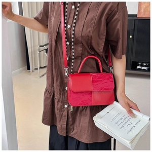 Detail of red crossbody bag with textured crocodile pattern and patchwork design on model