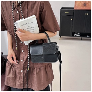 Detail of black patchwork handbag featuring mixed smooth and pleated leather textures