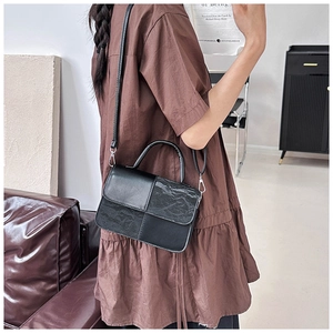 Detailed view of black textured patchwork leather shoulder bag with metallic strap hooks