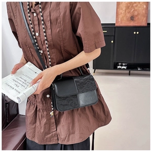 Detail of black crossbody bag featuring checkerboard拼接 textures and pleated leather design