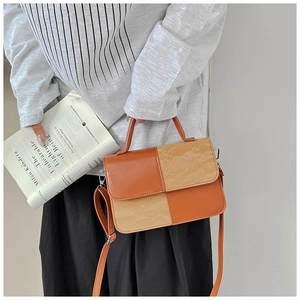 Detail of trendy color-block handbag with orange leather and beige pleated texture