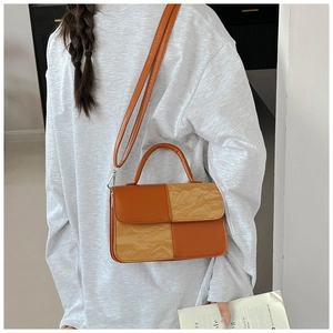 Detail of color-block crossbody bag with textured leather panels and top handle