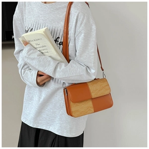 Detail of trendy color-block crossbody bag featuring orange leather and pleated texture