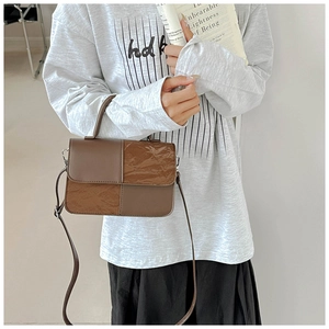 Detail showing retro brown patchwork texture and stitching on the trendy mini crossbody bag