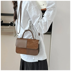 Detail of two-tone brown leather bag showing wrinkled texture and silver hardware