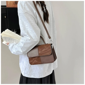 Detail of vintage coffee crossbody bag featuring textured patchwork and leather strap
