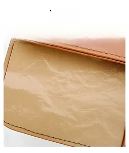 Detailed close-up of premium brown leather texture with precise stitching on small bag